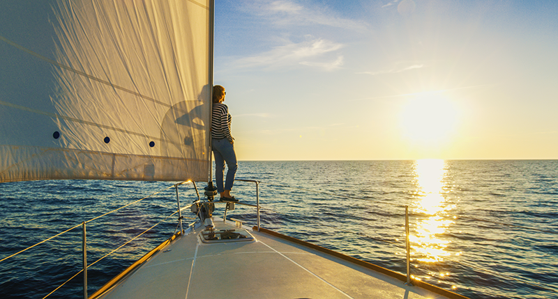 Woman standing on edge of boat overlooking water at sunset | 2024 State of the Insurance Market Insights from Alliant Private Client Leaders