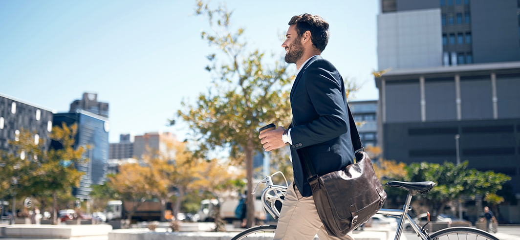 Young man walking in city with bike | Why young adults need their own insurance | Alliant Private Client