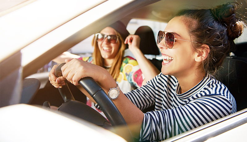 Young female driver and passenger laughing in car | Alliant Private Client